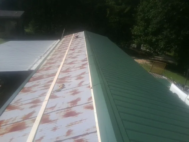 Old rusted panels beside newly installed green metal roofing — Wind Damage Roof Repair by Roofing Brothers in Wheat Ridge