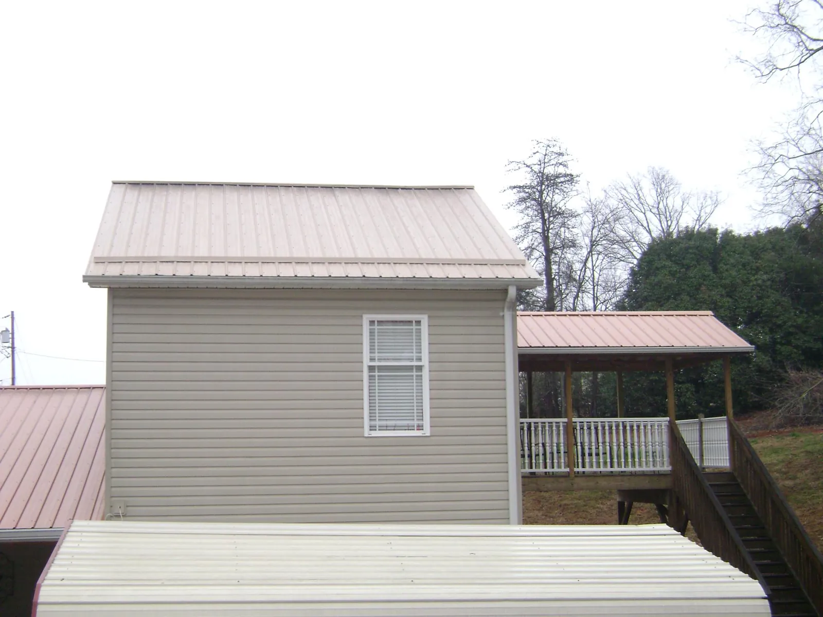 Tan metal roofs on a two story addition and attached porch, from a Roof Replacement job in Wheat Ridge
