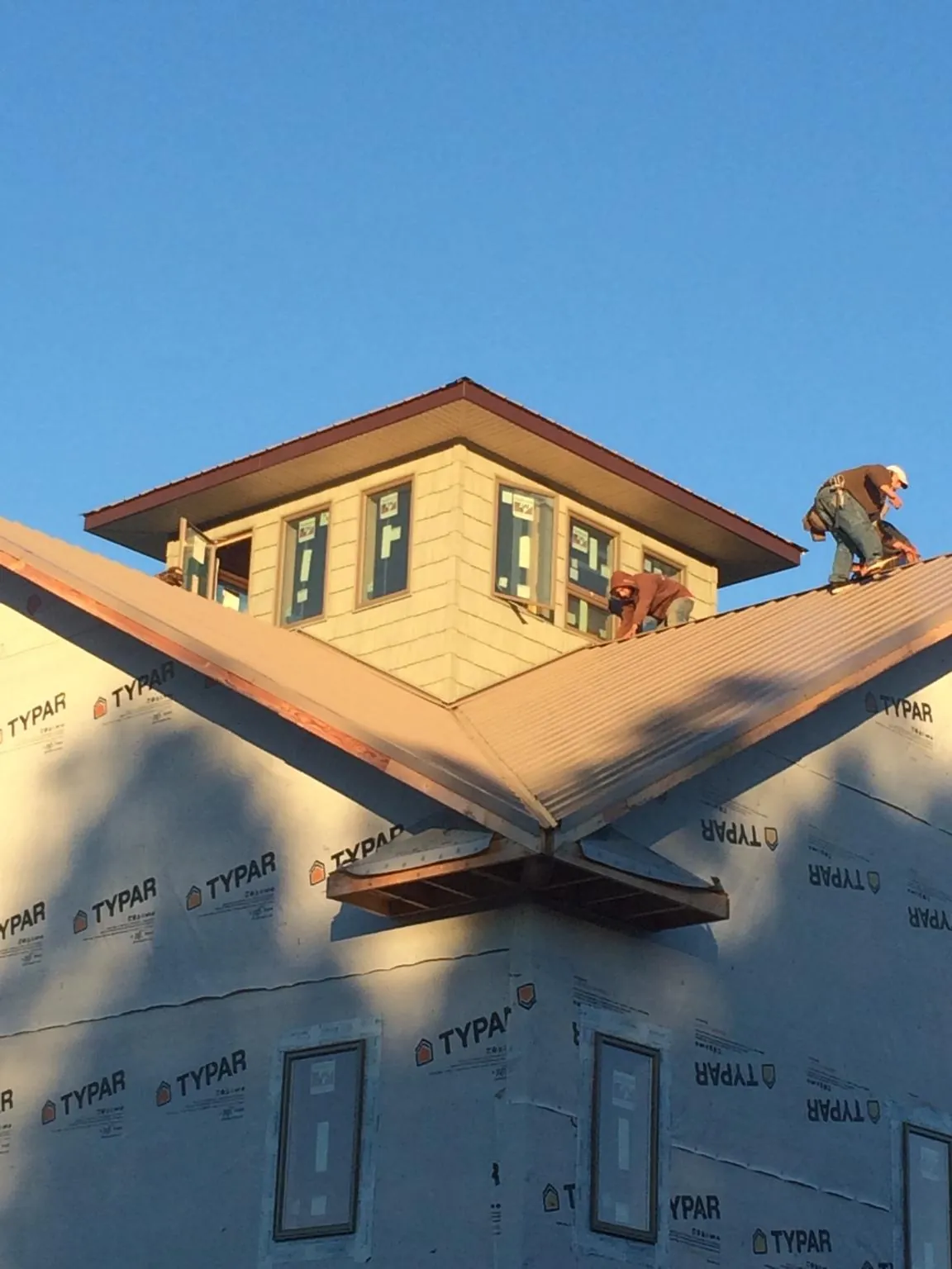 Roofers working around a rooftop cupola on a new metal roof at sunset — Roof Waterproofing in Wheat Ridge by Roofing Brothers